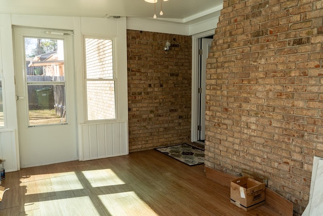 interior space featuring brick wall and light hardwood / wood-style flooring