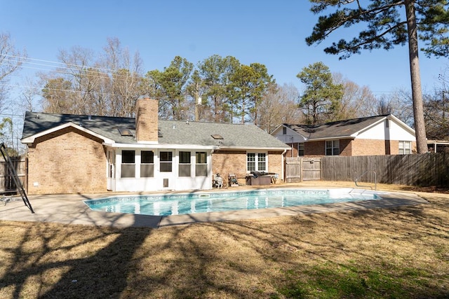 back of property with a yard, a fenced in pool, a patio, and a sunroom