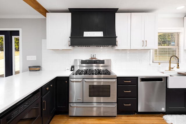 kitchen with ventilation hood, sink, decorative backsplash, appliances with stainless steel finishes, and white cabinetry