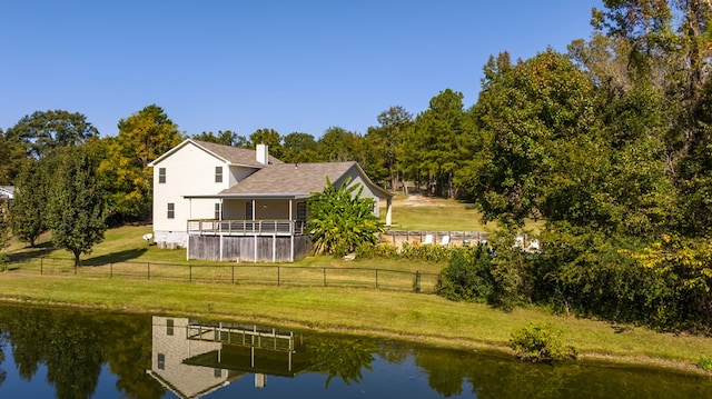 rear view of house featuring a water view and a lawn