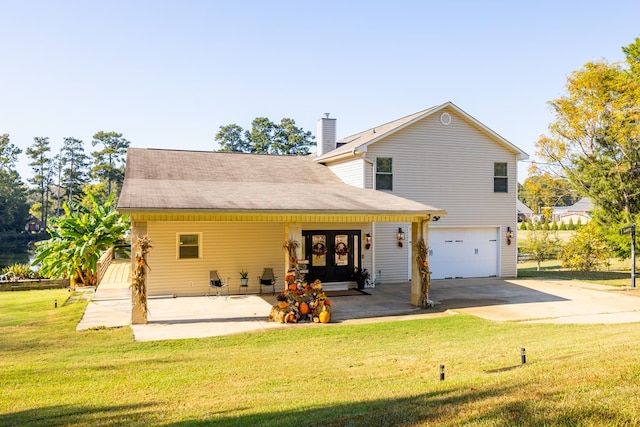 back of property with french doors, a garage, and a lawn