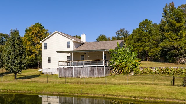 back of house with a lawn and a deck with water view