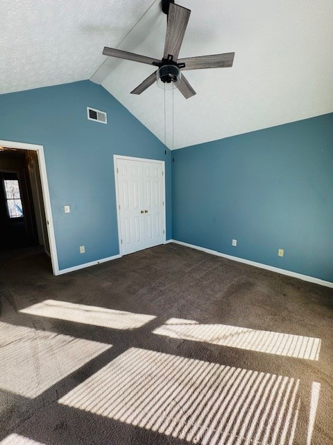 unfurnished bedroom with ceiling fan, dark colored carpet, a closet, and lofted ceiling