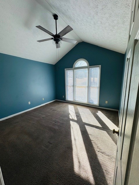 carpeted empty room with vaulted ceiling, ceiling fan, and a textured ceiling