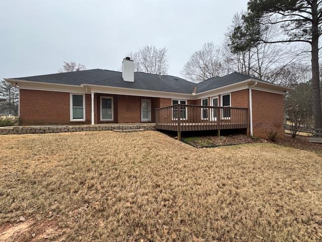 rear view of house featuring a yard and a wooden deck