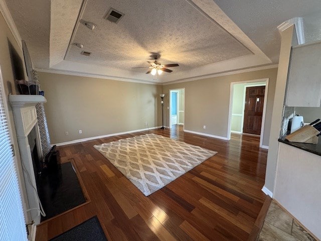 living room featuring ceiling fan, a raised ceiling, a textured ceiling, and dark hardwood / wood-style floors