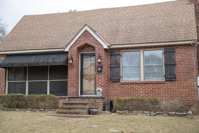 view of front of home featuring brick siding and roof with shingles