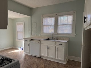 kitchen featuring white cabinets, dishwasher, range with gas stovetop, light countertops, and a sink