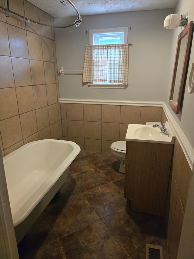 1704 18th St, Phenix City, AL 36867 - bathroom with tile walls, a freestanding tub, vanity, a textured ceiling, and a wainscoted wall
