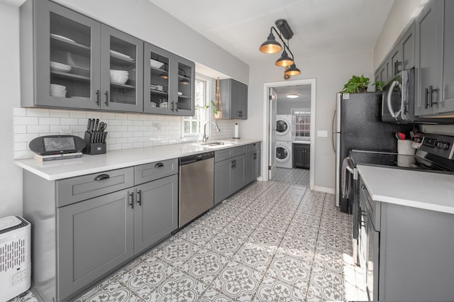 kitchen with appliances with stainless steel finishes, backsplash, gray cabinetry, and glass insert cabinets