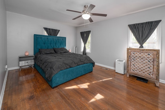 bedroom featuring baseboards, ceiling fan, wood finished floors, and visible vents