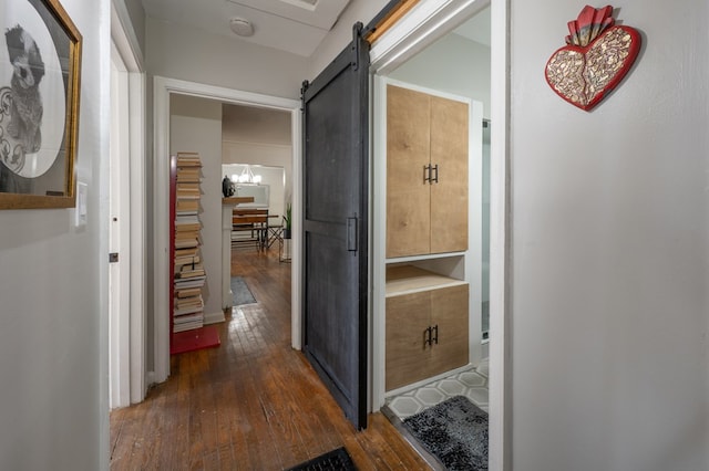 corridor featuring dark wood-type flooring and a barn door