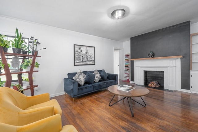 living room with crown molding, built in features, a brick fireplace, wood finished floors, and baseboards
