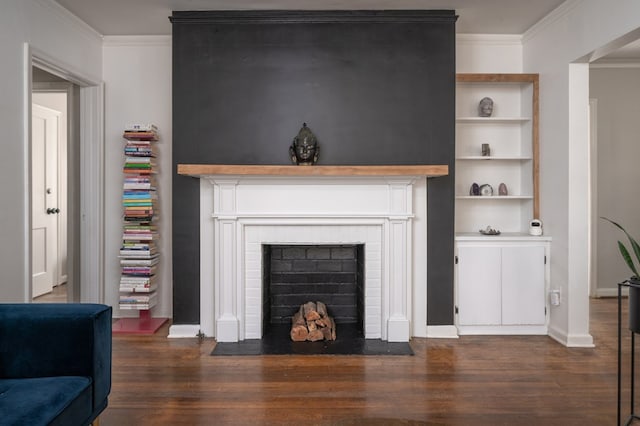 living room featuring crown molding, a fireplace, built in shelves, baseboards, and dark wood-style floors