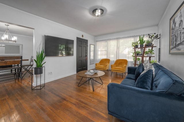 living area featuring an inviting chandelier, ornamental molding, baseboards, and hardwood / wood-style floors