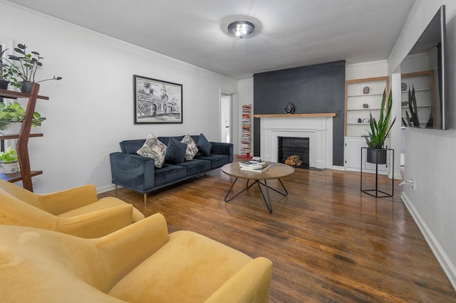 living room featuring crown molding, baseboards, a fireplace with flush hearth, and wood finished floors