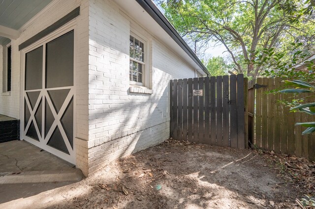 view of side of home with fence and brick siding