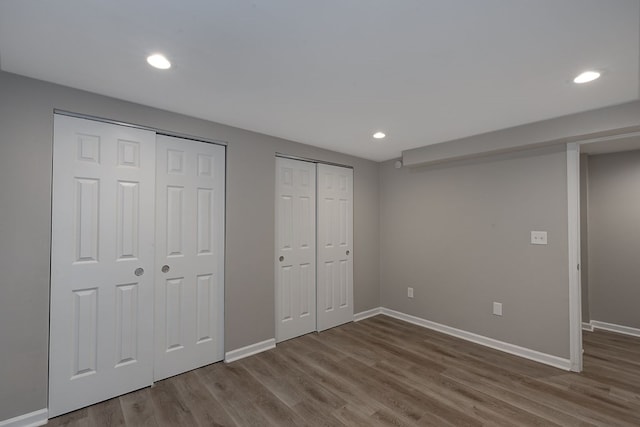 unfurnished bedroom with wood-type flooring and multiple closets