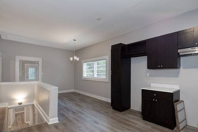 kitchen with light wood-type flooring, decorative light fixtures, dark brown cabinetry, and a notable chandelier