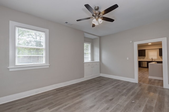 spare room featuring wood-type flooring, ceiling fan, and a healthy amount of sunlight