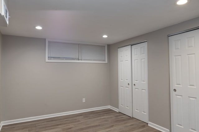 unfurnished bedroom featuring hardwood / wood-style floors and multiple closets