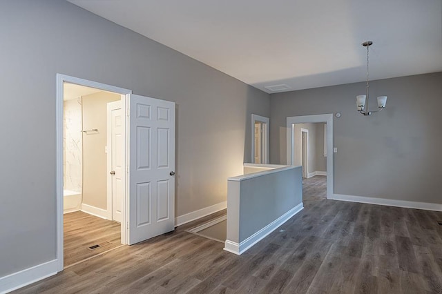 spare room featuring dark wood-type flooring and a notable chandelier