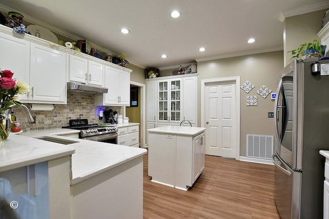 kitchen featuring white cabinetry, a center island, stainless steel appliances, tasteful backsplash, and light stone counters