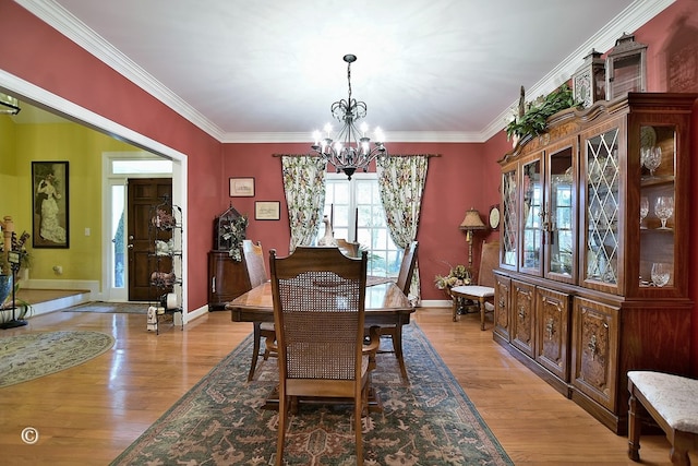 dining space featuring a chandelier, ornamental molding, and light hardwood / wood-style flooring