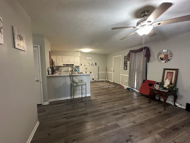 interior space featuring white cabinetry, dark hardwood / wood-style floors, kitchen peninsula, a textured ceiling, and a kitchen bar