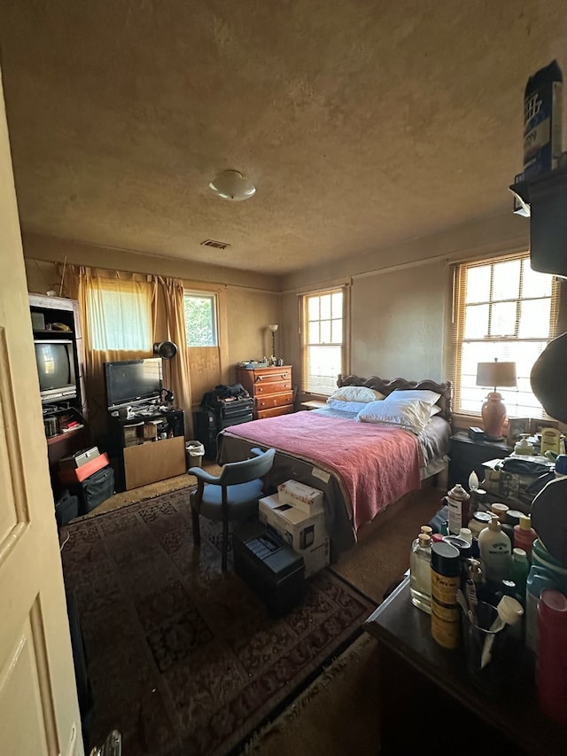 bedroom with a textured ceiling and multiple windows