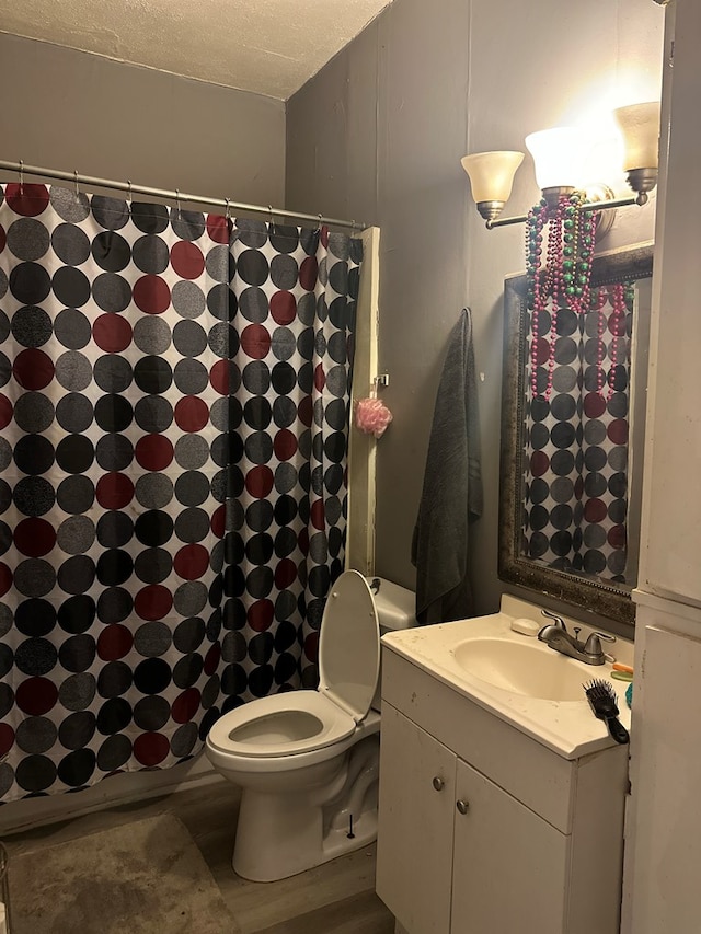 bathroom featuring vanity, hardwood / wood-style flooring, a shower with shower curtain, toilet, and a textured ceiling