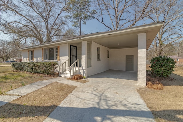 view of front facade with entry steps, a carport, and concrete driveway