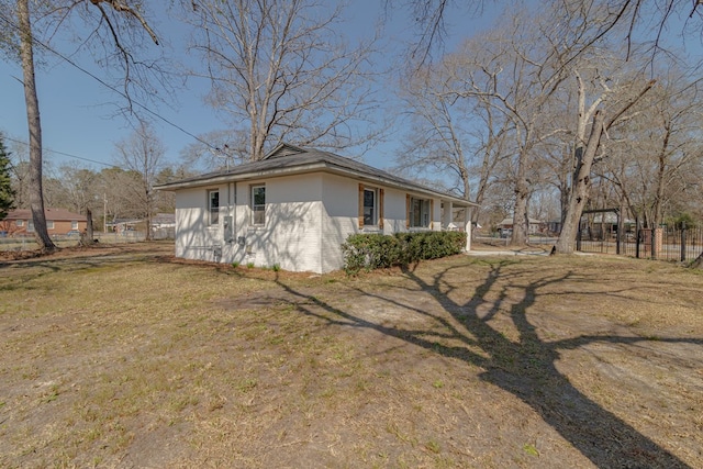 view of side of property featuring stucco siding, fence, and a lawn