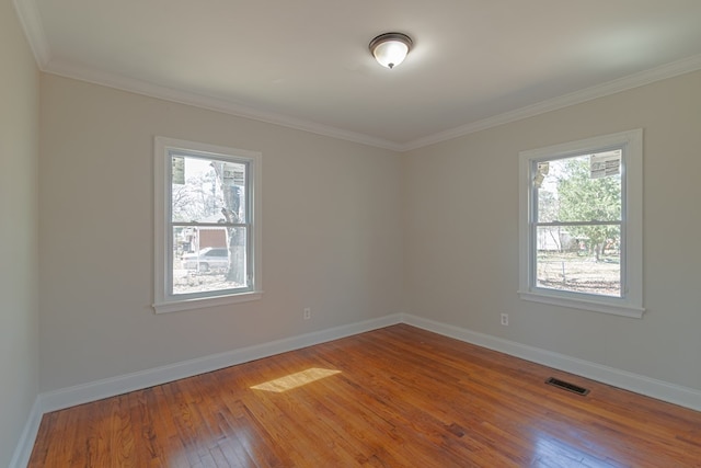 empty room featuring baseboards, visible vents, hardwood / wood-style flooring, and a healthy amount of sunlight