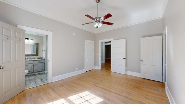 unfurnished bedroom featuring baseboards, ensuite bathroom, crown molding, light wood-type flooring, and a sink