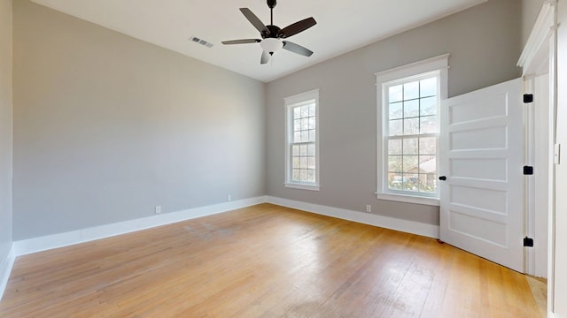 spare room with visible vents, a ceiling fan, vaulted ceiling, light wood-type flooring, and baseboards