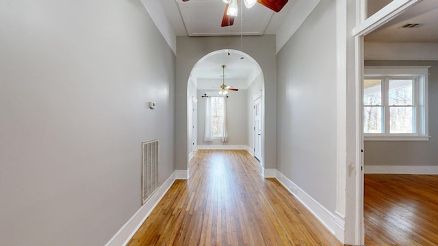 doorway to outside featuring light wood finished floors, baseboards, visible vents, and arched walkways