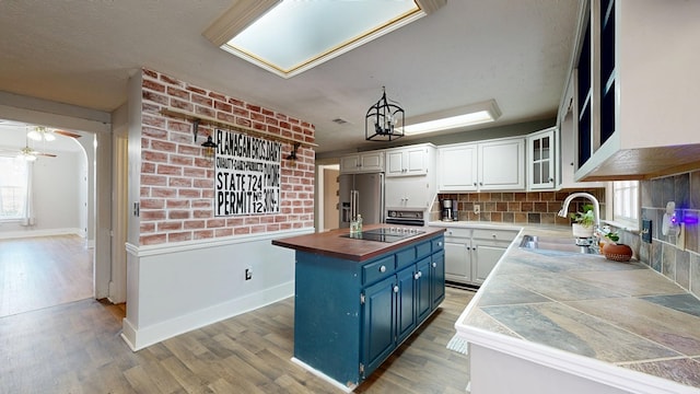 kitchen featuring butcher block counters, a sink, white cabinets, blue cabinetry, and a center island