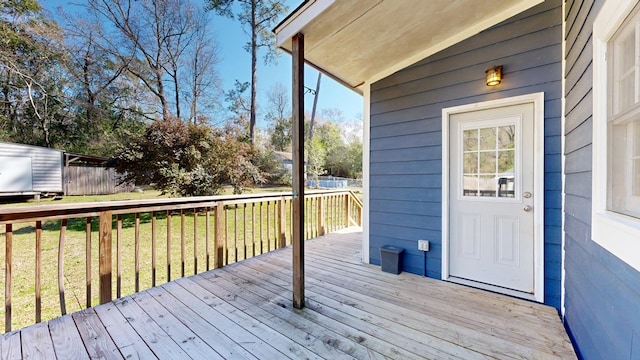 wooden deck featuring a storage unit, a lawn, and fence