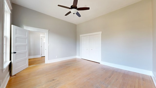 unfurnished bedroom featuring a ceiling fan, light wood-style flooring, baseboards, and a closet