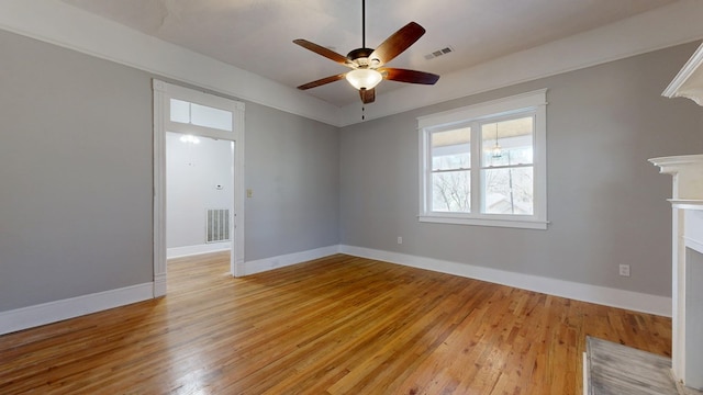 unfurnished room with ceiling fan, light wood-type flooring, visible vents, and baseboards