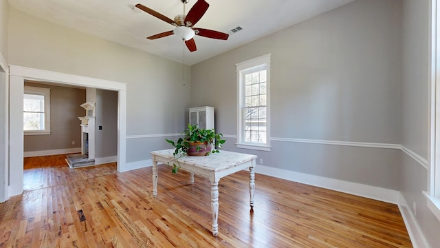 interior space featuring a ceiling fan, light wood-type flooring, visible vents, and baseboards