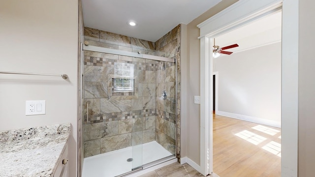 full bathroom with baseboards, ceiling fan, wood finished floors, vanity, and a shower stall