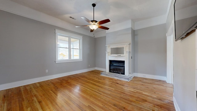 unfurnished living room with a ceiling fan, a glass covered fireplace, light wood-style flooring, and baseboards