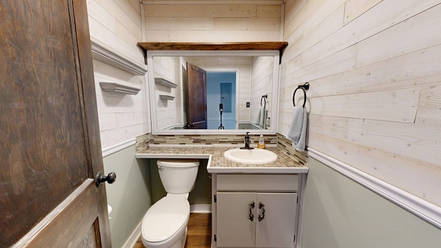 bathroom featuring vanity, toilet, and wooden walls