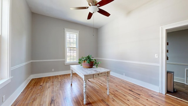 unfurnished office featuring light wood-type flooring, baseboards, and a ceiling fan