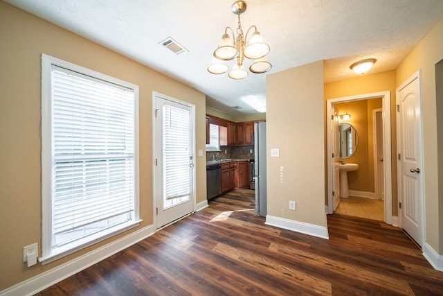 unfurnished dining area featuring dark hardwood / wood-style floors, sink, a notable chandelier, and a textured ceiling