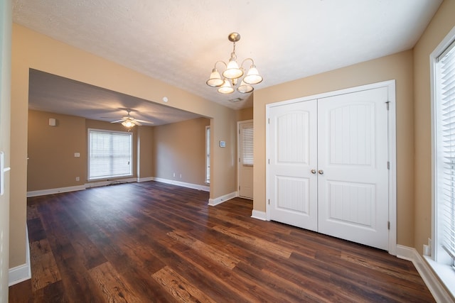 interior space featuring ceiling fan with notable chandelier, dark wood-type flooring, and a textured ceiling