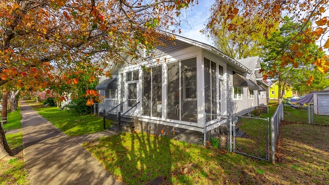 view of side of home with a yard, a gate, fence, and a sunroom