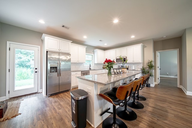 402 Lee Road 2203, Phenix City, AL 36870 - kitchen with stainless steel appliances, a center island, light stone counters, decorative backsplash, and dark wood-type flooring